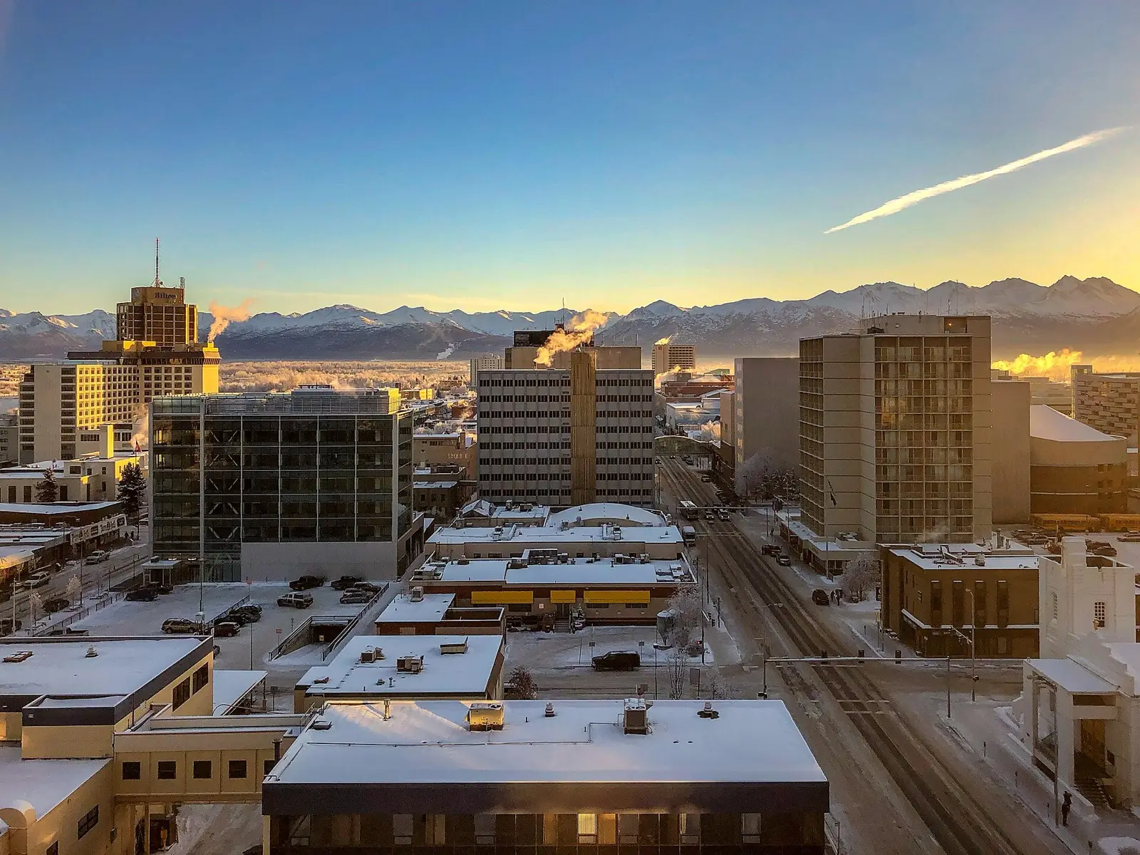 Downtown Anchorage on a clear winter morning with snow on the roofs and the Chugach Mountains behind